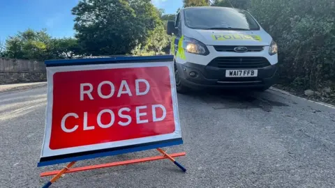 Road closed sign and police van