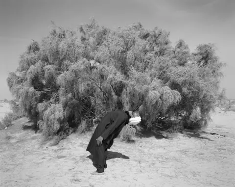 Edgar Martins Portrait of a man standing by a bush