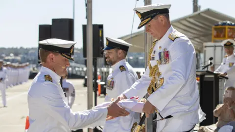 COMMANDER AUSTRALIAN FLEET/TWITTER Australian naval officials conduct a ceremony at the commissioning of HMAS Supply