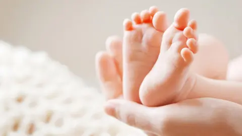 Getty Images Baby feet held in mum's hands