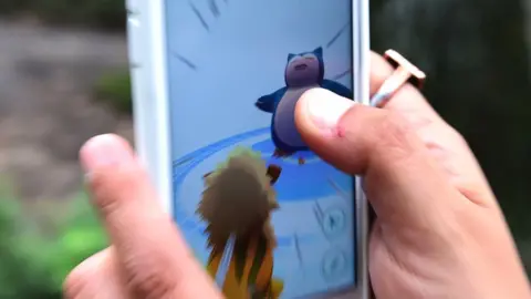 Getty Images A person plays Pokemon Go - attempting to catch a Snorlax with an Arcanine