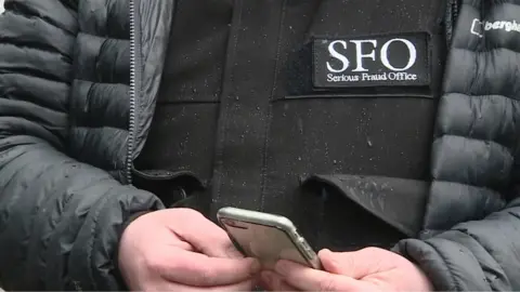 BBC Close-up of a man's jacket bearing the SFO log