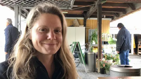 Henrike Hahn is pictured smiling at the camera under a shelter with plants in the background