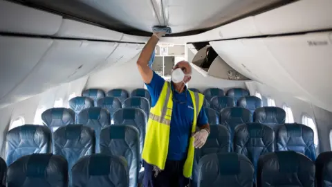 Getty Images An airline worker wearing a face mask inspects a plane