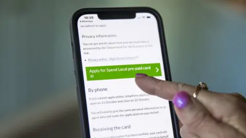 PA Media A woman using a web browser on her mobile phone to apply for the Spend Local voucher