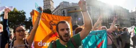 Getty Images Protesters with 'democracy' flags chant outside the Catalan economy ministry