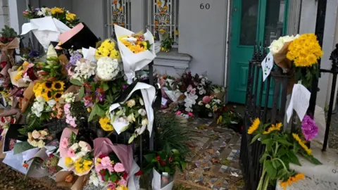 EPA Floral tributes left outside Mr Baird's home
