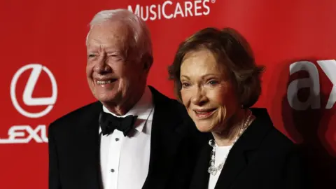 Reuters Jimmy Carter and his wife Rosalynn Carter posing in front of a red backdrop