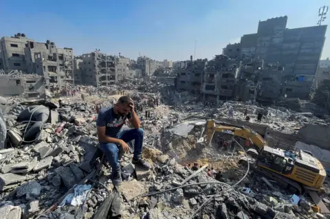 Reuters A man puts his hand on his head while Palestinians search for survivors underneath destroyed buildings in Jabalia's Fallujah area (1 November 2023)