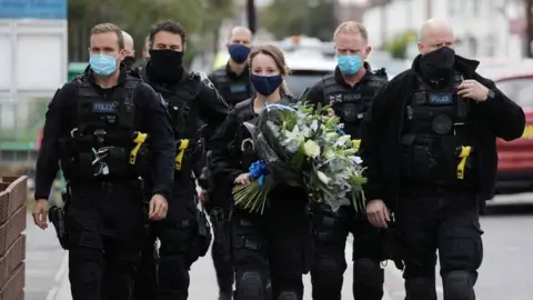 Reuters Police officers arrive to pay respects outside the custody centre where a British police officer has been shot dead in Croydon, south London