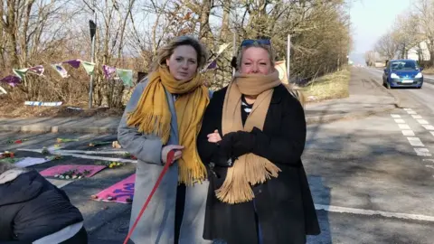 Two women stand next to flowers