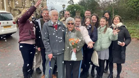 The family of Mr and Mrs Davis throw confetti over the couple as they pose for a family photo