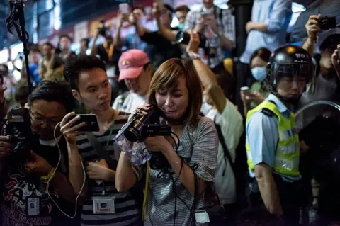 AFP/Getty Images A local Hong Kong journalist (C) cries as she films a colleague who was pepper sprayed after trying to stop police from pushing her, in the Mongkok district of Hong Kong on 17 October 2014