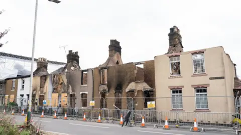 PA Media A row of fire damaged terraced houses in Wennington