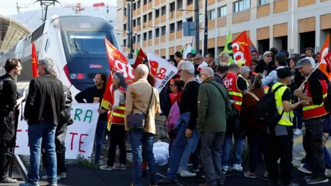 Reuters Workers on strike hold CGT labour union flags as they walk on railway tracks to block a TGV high speed train during a demonstration at the train station on the eve of the ninth day of national strike and protests