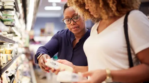 Getty Images Women comparing cost of cheese