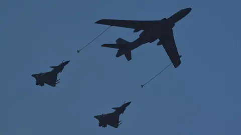 Getty Images A Xian H-6U in-flight refuelling tanker (C) flies in formation with a pair of Chengdu J-10 multirole fighter