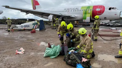 BBC Firefighters treat an actor playing a casualty on the ground