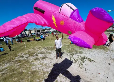 Reuters Man flying a large pink and purple kite.