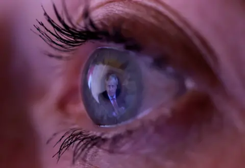 Phil Noble / Reuters A close up of a woman's eye with the image of Boris Johnson reflected in her iris