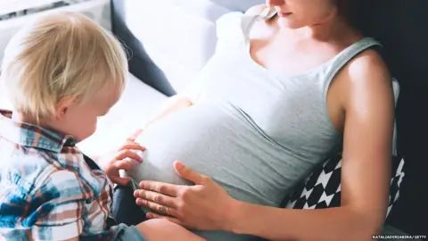 NataliaDeriabina/Getty Pregnant mother with young child