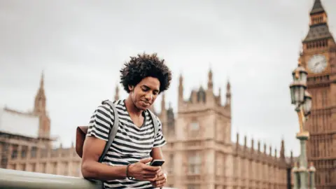 Getty Images A man using a smart-phone outside the houses of parliament.