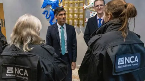 Getty Images Rishi Sunak speaks with National Crime Agency (NCA) officers.