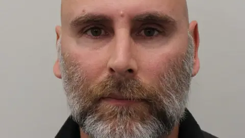 Met Police Police custody image of Nathan Arnold, a bald man with a beard