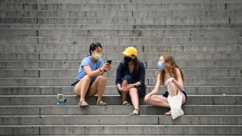 Getty Images People wearing protective face masks sit on the steps of the Metropolitan Museum of Art during the coronavirus pandemic on May 30, 2020 in New York City