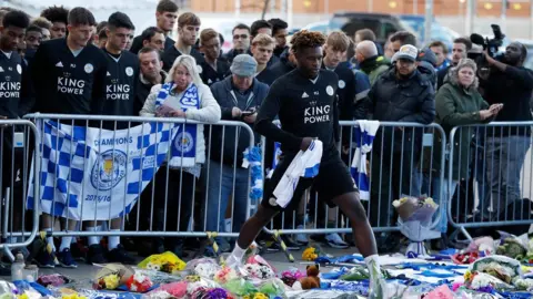 Reuters Darnell Johnson steps through tributes to lay football shirt