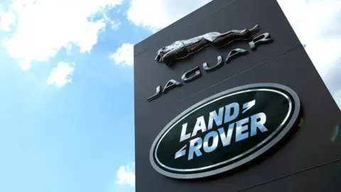 Andrew Boyers/Getty Jaguar Land Rover logo against a blue sky