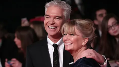 PA Media Philip Schofield and wife Stephanie arriving for the 2014 National Television Awards at the O2 Arena, London.