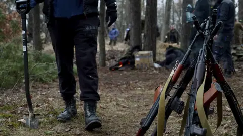 People digging trenches in a forest near Ukraine's capital Kyiv to block a Russian advance