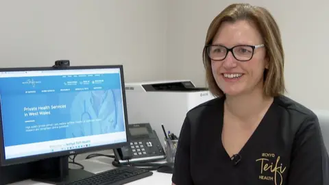 BBC Dr Beth Howells smiling while sitting in front of a computer