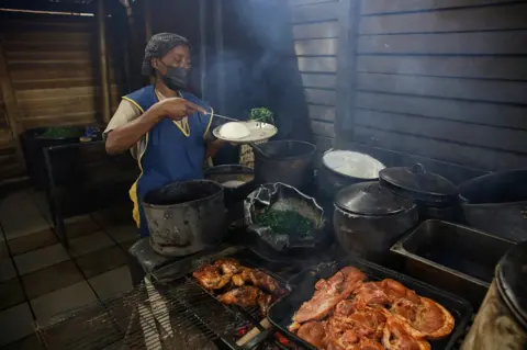 EPA A chef dishes up a traditional meal of Sadza and green vegetables for a customer at the popular Little Mereki restaurant in Harare, Zimbabwe, 08 April 2022.