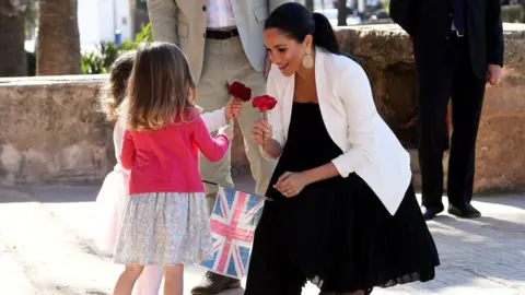 Reuters Duchess of Sussex is given flowers by two children during a visit to Morocco