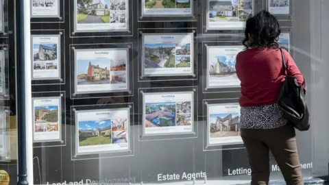 Getty Images People looking at houses for sale in an estate agents window in Cirencester, Gloucestershire