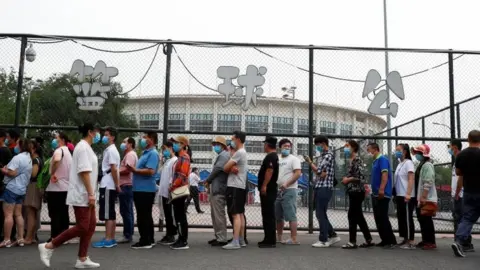Reuters People queuing for a nucleic acid test on Wednesday - most people need a negative test before leaving the city, while others are banned entirely