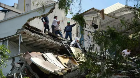 AFP People stand at a building which collapsed after a quake rattled Mexico City