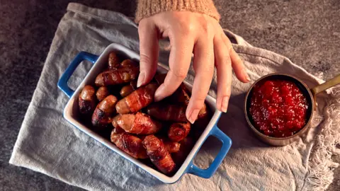 Getty Images Woman reaching for pigs in blankets