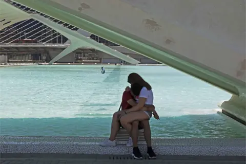 Mike Ribbans A couple embracing whilst holding their phones