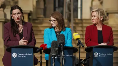 PA Media Deputy First Minister Emma Little-Pengelly (left) with First Minister Michelle O'Neill (right) and Minister of Finance Caoimhe Archibald