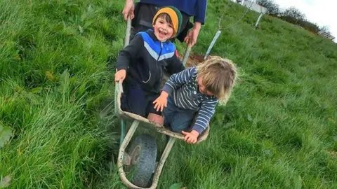 Tamasin Pemberton Two small boys in wheel barrow