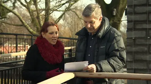 BBC Francisca and Colin looking at photographs of the condition of their former rented home