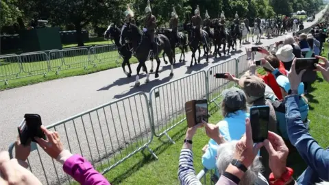 Getty Images The household cavalry leads the procession as crowds capture them on their phones