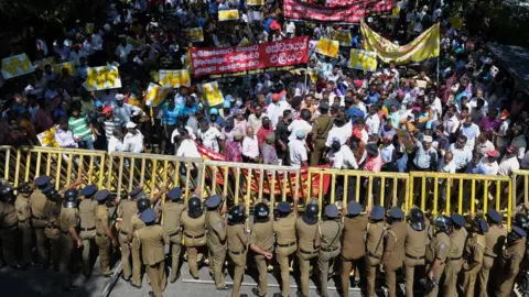 Getty Images Sri Lankan police stand guard during a protest against the proposed sale of a stake in a loss-making port to a Chinese company in Colombo