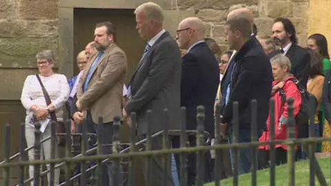 Mourners gather outside New Laigh Kirk in Kilmarnock