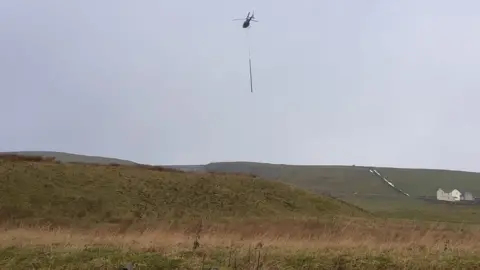 Northern Powergrid Helicopter carries new pole above countryside