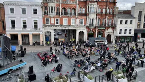 Dawn Gerber/BBC People watching funeral in Cornhill