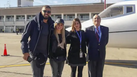 AFP Gerard Piqué (left) alongside his wife, Shakira, and airport staff in Rosario